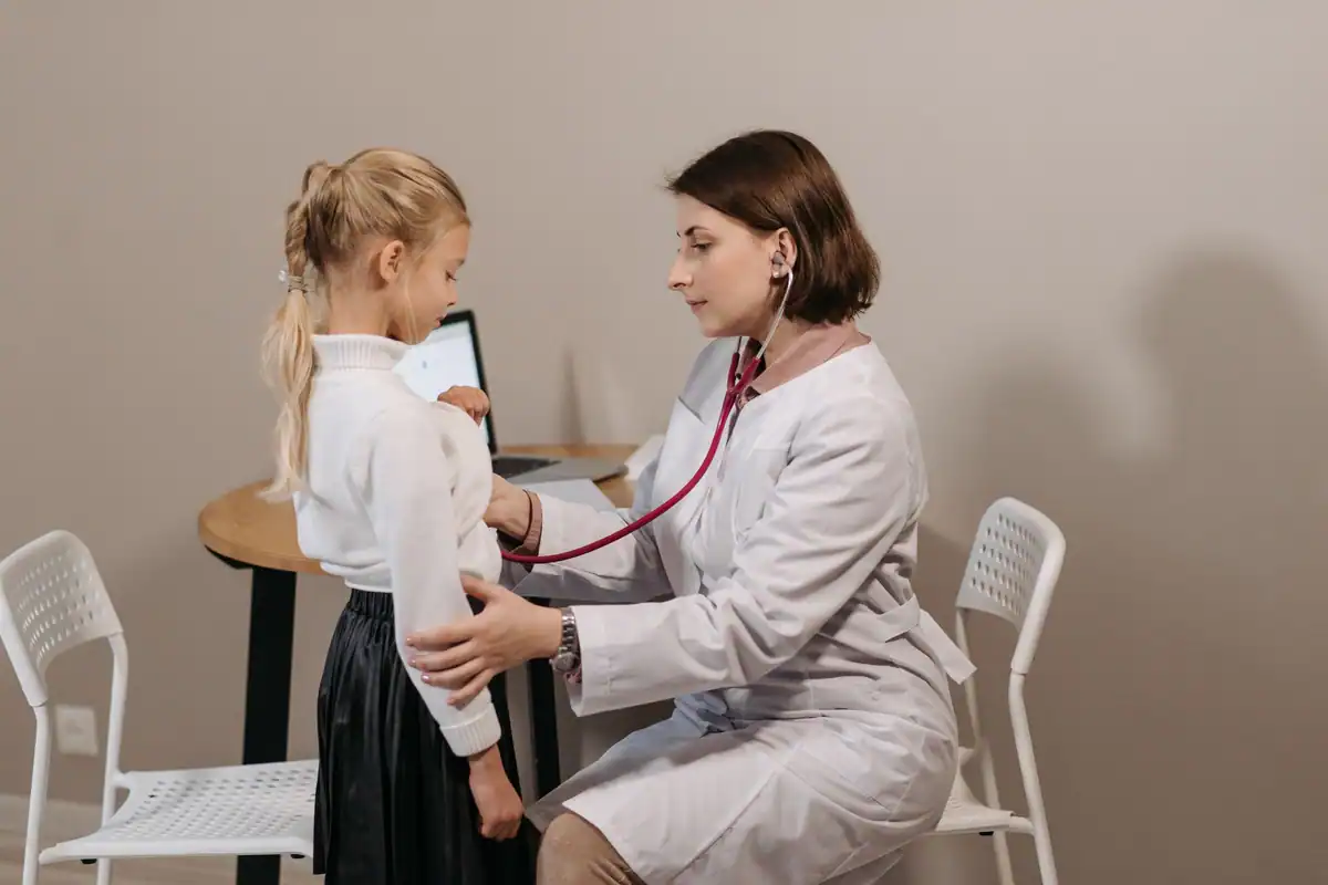 Pediatră care ascultă cu stetoscopul pieptul unei fetițe în timpul unui control periodic