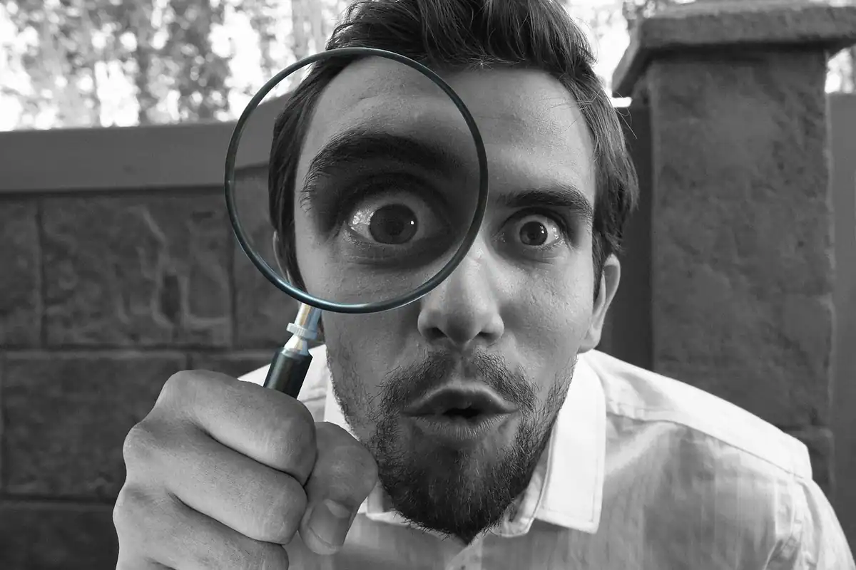 Medic dermatolog care examinează o aluniță cu o lupă, în timpul unui control al pielii