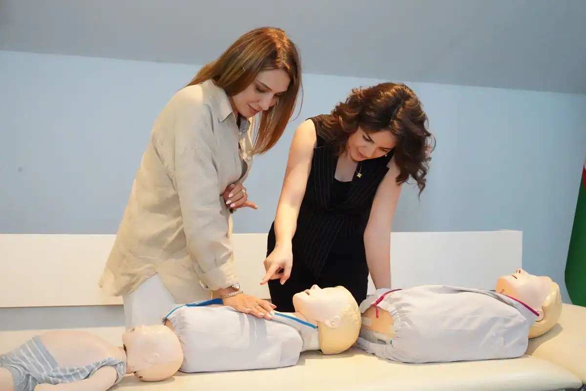 Două femei exersează resuscitarea pe manechine de instruire la un curs de prim ajutor