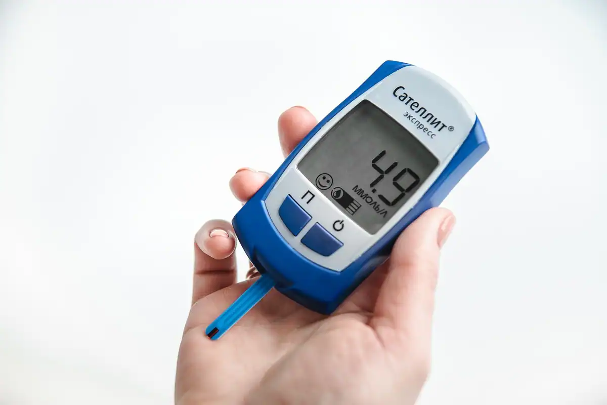 Glucometru și bandelă de testare așezate pe o masă, pentru măsurarea glicemiei