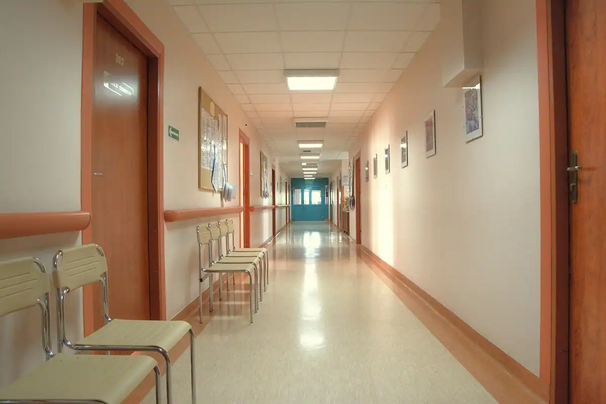 Coridor luminos de spital, cu uși și scaune de așteptare pe stânga
