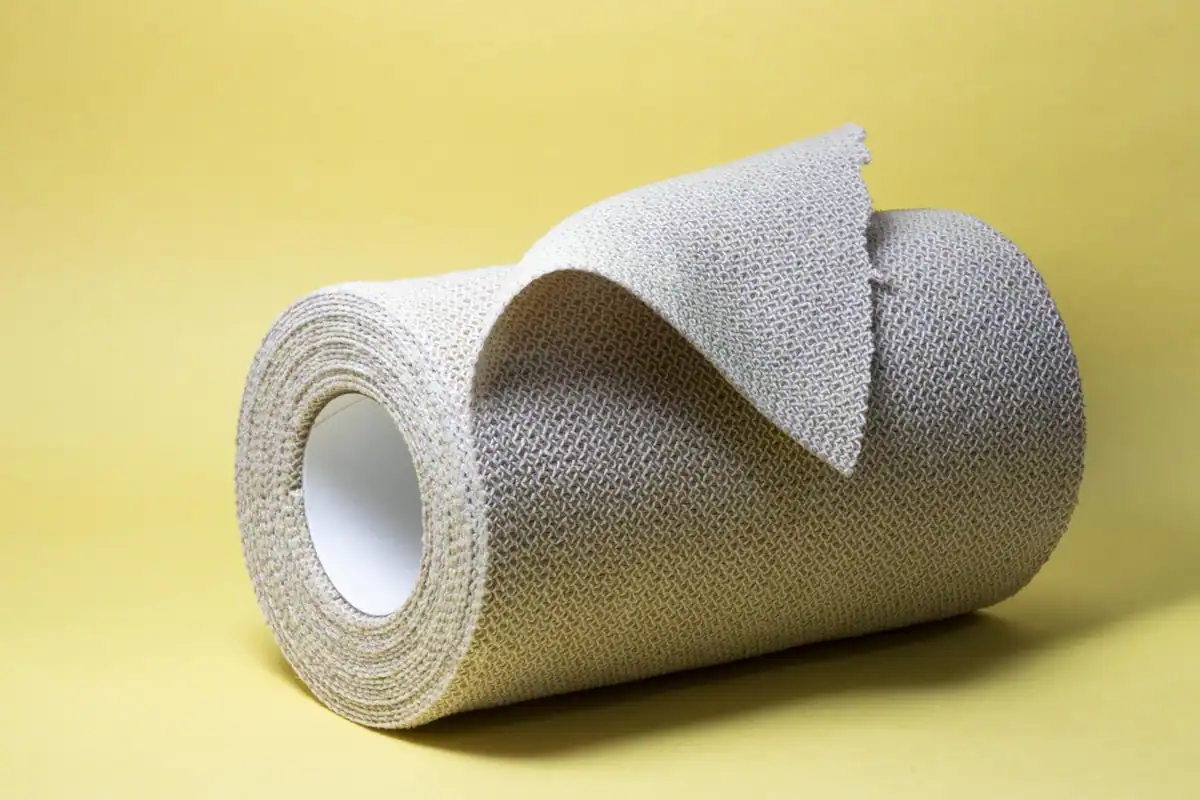 Rolă de bandaj elastic gri pe un fundal galben