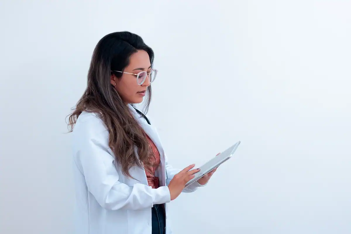 Doctoriță în halat alb care consultă o tabletă într-un cabinet luminos
