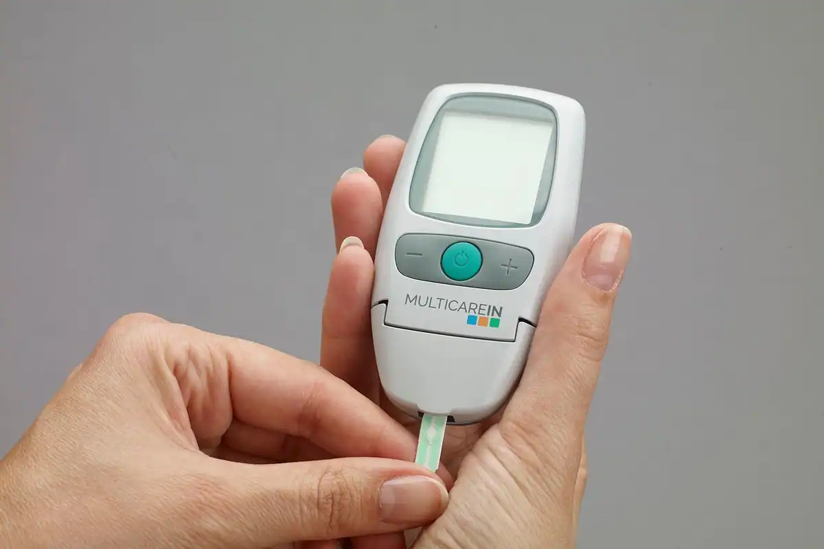 Mâini care folosesc un glucometru pentru a verifica nivelul zahărului din sânge