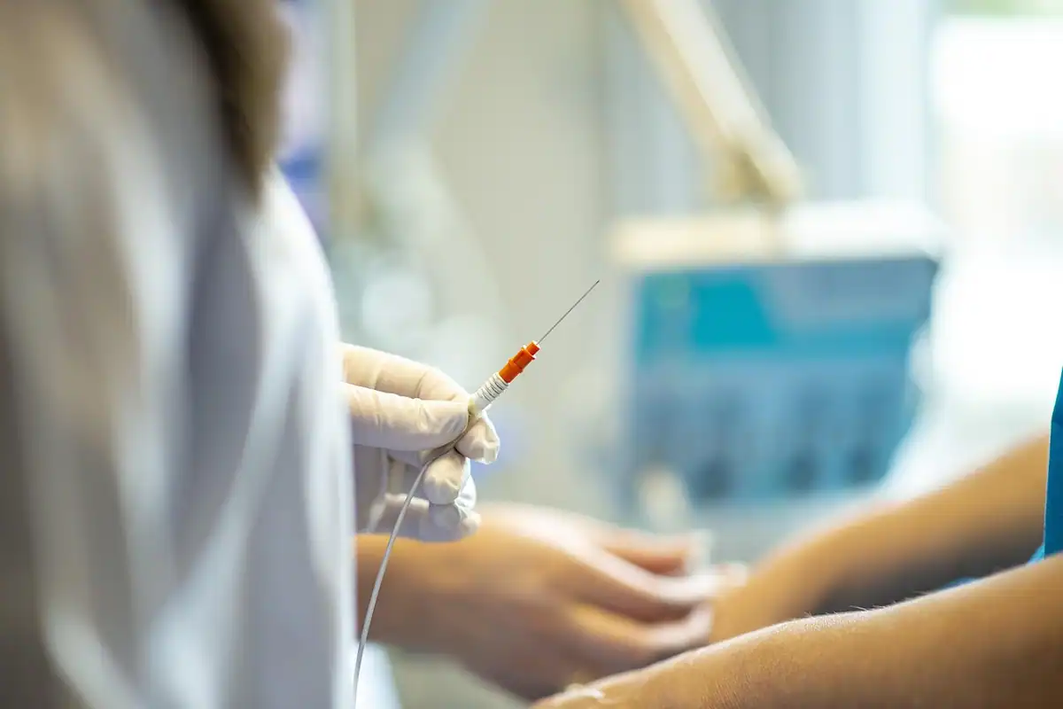 Mâini cu mănuși care pregătesc o injecție, în fundal neclar, într-un cabinet