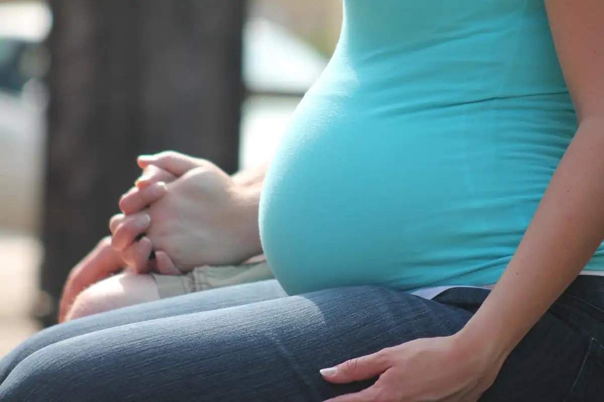 Femeie însărcinată care își ține mâinile pe burtă, într-o discuție despre vaccinarea în sarcină
